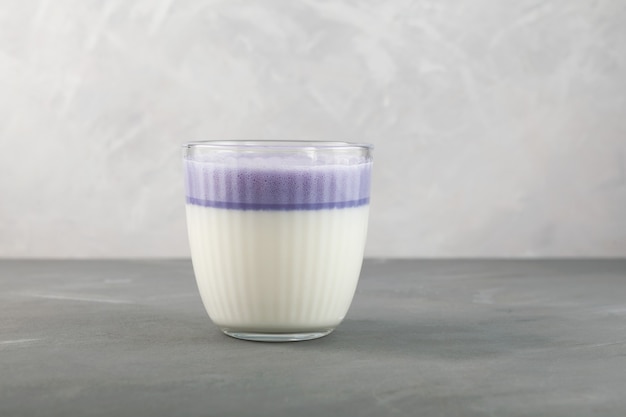 Latte di patata viola dolce in vetro su sfondo grigio Bevanda rinfrescante sana coreana