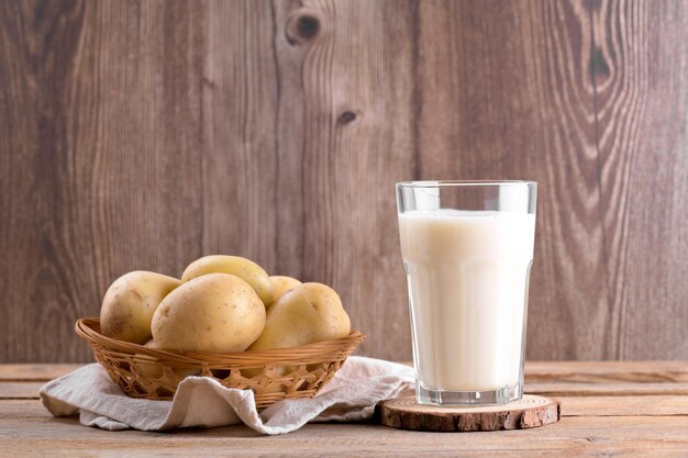 Latte di patate vegane e patate su fondo di legno marrone primo piano latte alternativo a base vegetale