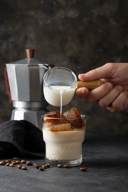 Latte di versamento della mano di vista laterale nella tazza di caffè