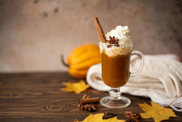 Latte di zucca con panna montata e cannella su un tavolo di legno