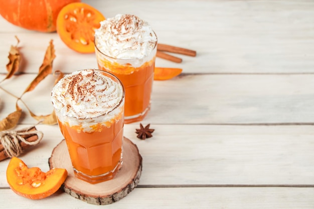 Latte di zucca con panna montata su fondo di legno chiaro Frullato piccante caldo Bevanda vegana vegetale