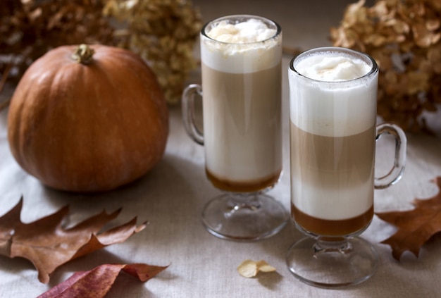 Latte di zucca fatto in casa in bicchieri alti e zucca su una tovaglia di lino. Stile rustico.