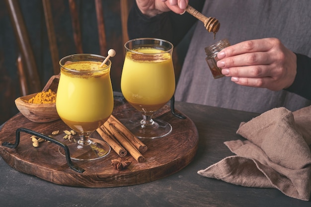 Latte dorato alla curcuma con bastoncini di cannella e miele. Bevanda ayurvedica salutare. Bevanda disintossicante naturale asiatica alla moda con spezie per vegani. Copia spazio.