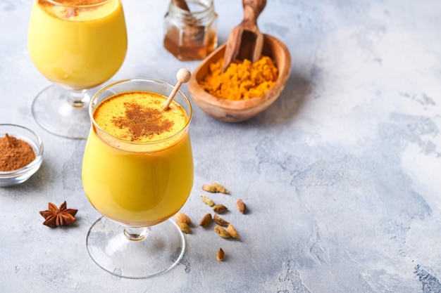 Latte dorato alla curcuma con bastoncini di cannella e miele. Bevanda ayurvedica salutare. Bevanda disintossicante naturale asiatica alla moda con spezie per vegani. Copia spazio.