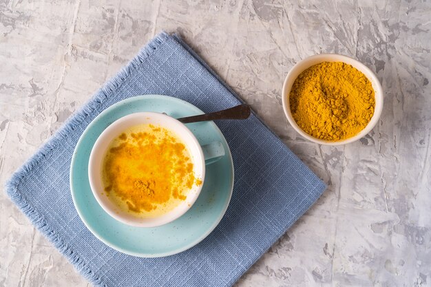 Latte dorato della curcuma con polvere di curcuma in una tazza