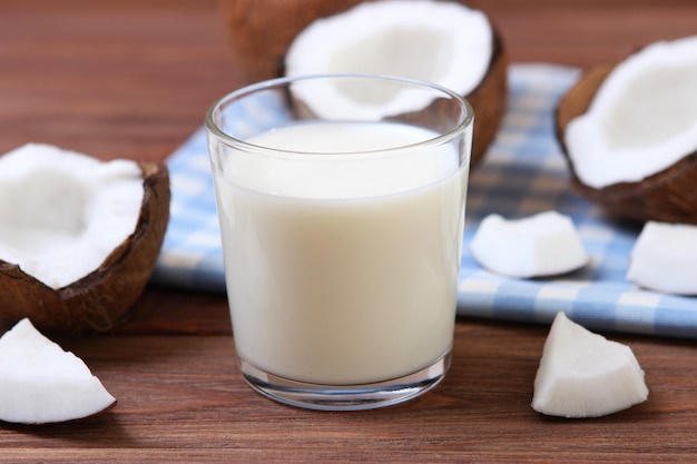 Latte e noci di cocco rotte sul tavolo latte vegetale una bevanda vegetariana