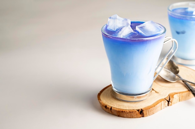 Latte ghiacciato con piselli a farfalla blu Latte matcha blu rinfrescante in tazze di vetro con cubetti di ghiaccio Spazio per la copia