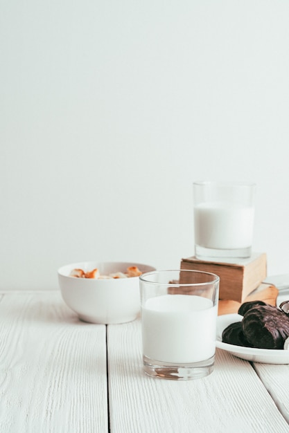 Latte in un bicchiere, marshmallow e cracker su uno sfondo bianco.