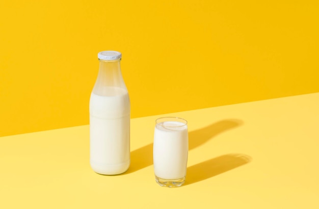 Latte in vetro e bottiglia minimalista su sfondo giallo