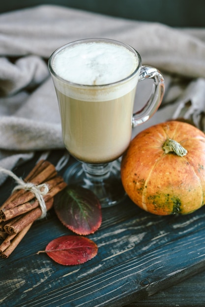 Latte piccante della zucca su una tavola di legno con un maglione