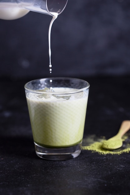 Latte verde caldo di matcha con latte di mandorla su una priorità bassa nera