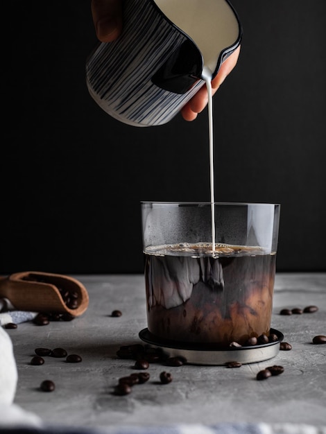 Latte versato in un bicchiere di caffè su sfondo nero