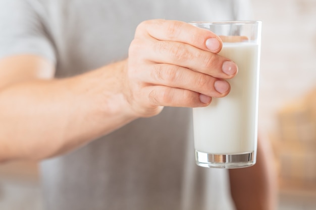 Latticini. Nutrizione equilibrata. Primo piano di un bicchiere di latte di soia in mano dell'uomo. .