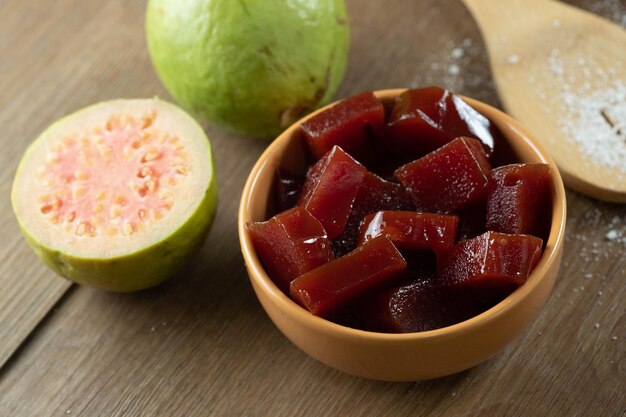 Lattina gialla con marmellata di guava tagliata a cubetti con guaiave sullo sfondo sul tavolo di legno