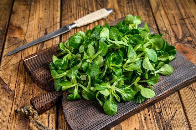 Lattuga di agnello verde crudo fresco Foglie di insalata di mais su un tagliere di legno