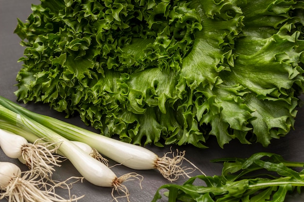 Lattuga verde lascia cipolle verdi fresche con radici e foglie di rucola Primo piano