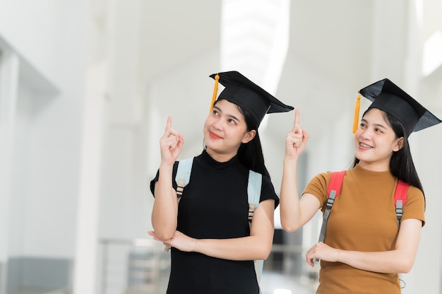 Laureate femminili che indossano cappelli neri, nappe gialle, sorridenti e felici il giorno della laurea