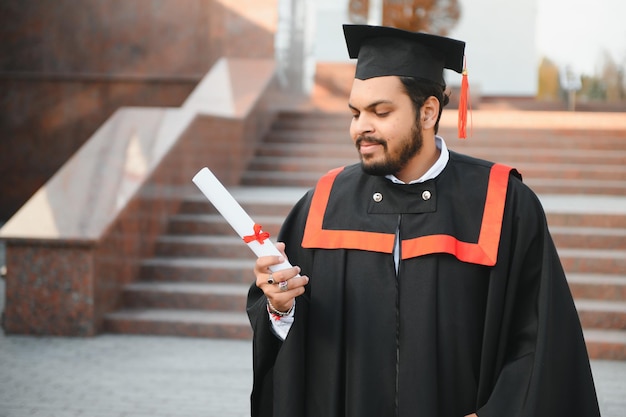 Laureato indiano in abito di laurea con diploma nello spazio della copia del campus universitario