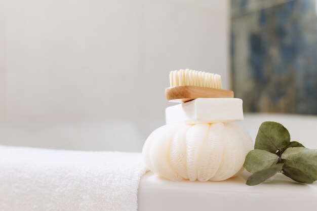 Lavabo in bagno bianco con accessori da bagno. Concetto di pulizia dell'hotel. concetto di famiglia. Asciugamano, sapone, spazzola per piedi, asciugamano bianco e ramo di eucalipto con foglie verdi. Bagno elegante