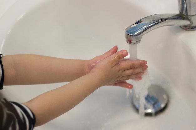 Lavaggio a mano del bambino nel lavabo.