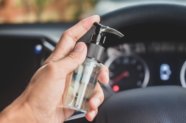 Lavaggio e pulizia delle mani con gel di alcol per la prevenzione del virus Corona in auto, alcool 70%