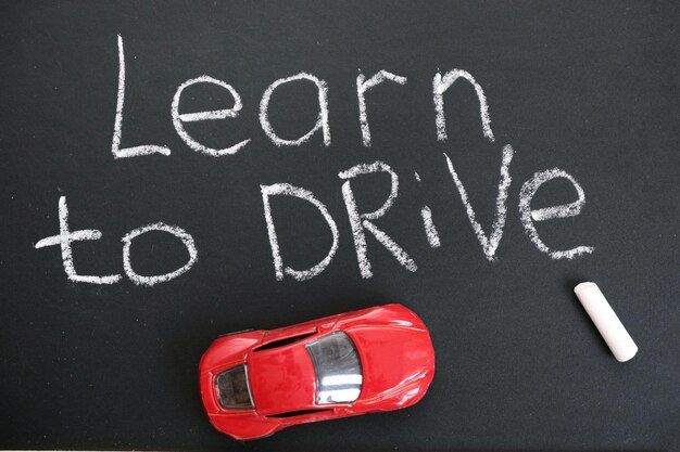 Lavagna scuola guida Composizione educativa e creativa con la didascalia Impara a guidare segnali stradali modello di auto giocattolo