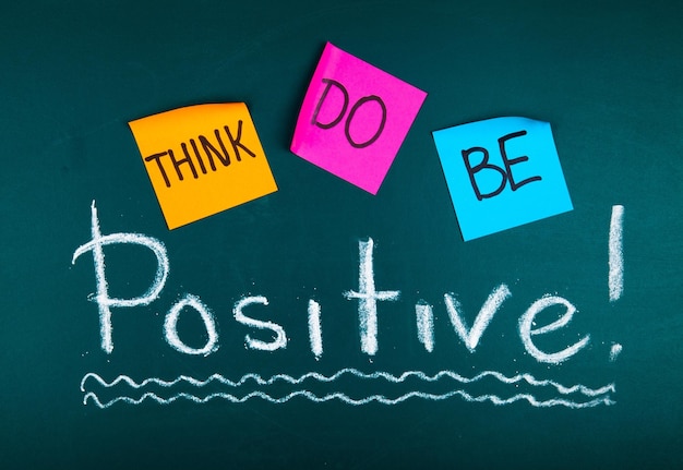 Lavagna verde con note appiccicose e parole "Think to Be Positive" su sfondo verde