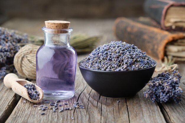 Lavanda secca in ciotola e bottiglia di olio essenziale di lavanda o libri d'acqua infusi e lavanda