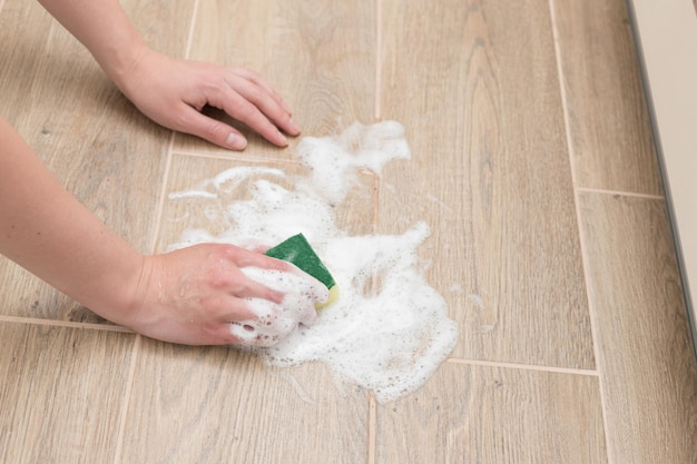 Lavare il pavimento con una spugna per la pulizia con una pulizia a schiuma per primo piano