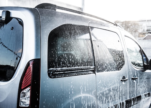 Lavare l'auto con il sapone. Primo piano concetto di auto pulita all'autolavaggio.