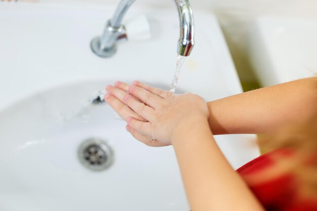 Lavare le mani dei bambini sotto il rubinetto del bagno
