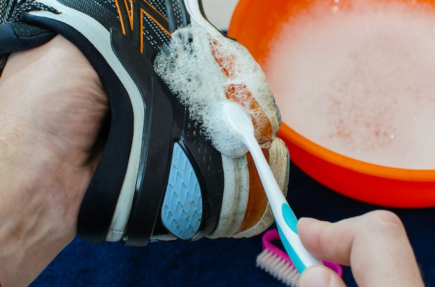 Lavare le scarpe da ginnastica sporche. Pulizia della suola della scarpa da corsa. Lava le scarpe da ginnastica sporche, pulisci le scarpe. lavare le scarpe da ginnastica. pulire le scarpe da trail running