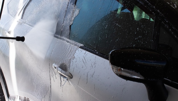 Lavare un'auto argentata dalla sporcizia in un autolavaggio self-service