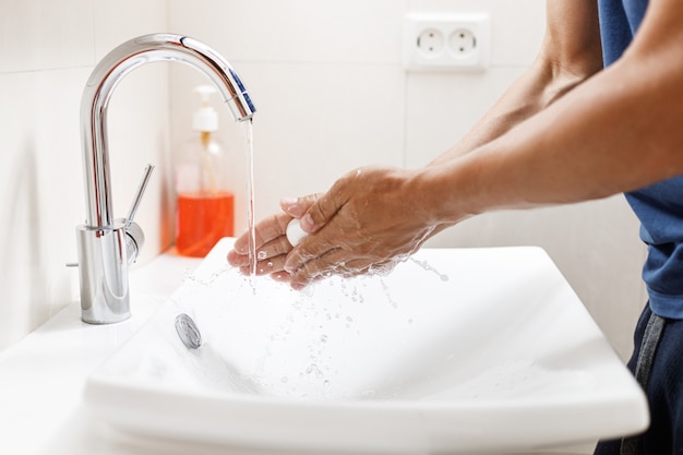 Lavarsi le mani con il sapone. Uomo che pulisce le mani in un bagno.