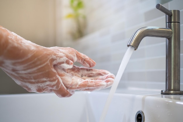 Lavarsi le mani con sapone e lavare con acqua corrente. Primo piano di donne scrub sapone per le mani con lavabo. Il concetto di igiene delle mani e giorni di lavaggio delle mani in tutto il mondo. Ridurre l'infezione Covit-19