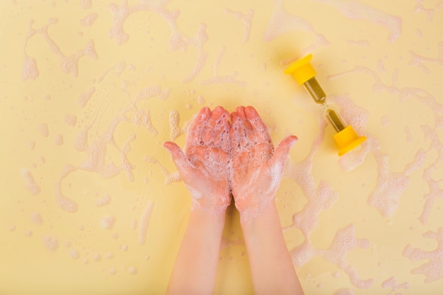Lavarsi le mani concetto lavarsi le mani a casa concetto di coronavirus mani del bambino in schiuma su alta qualità gialla...