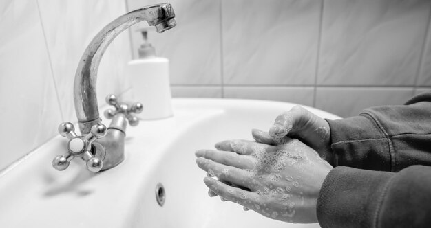 Lavarsi le mani strofinando con sapone uomo per la prevenzione del coronavirus foto in bianco e nero