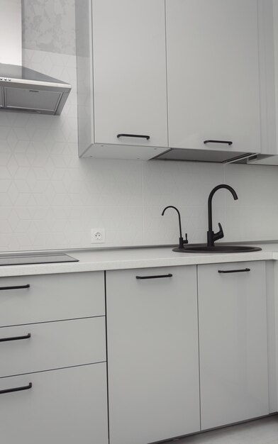 Lavello da cucina nero con controsoffitto in granito bianco minimalista, armadi grigi e isolante nero