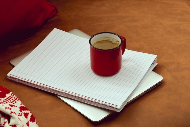 Lavora durante le vacanze di Natale Area di lavoro sul divano con una tazza di caffè accanto al blocco note