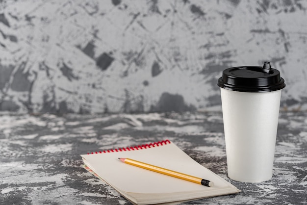 Lavorando in movimento. Tazza di caffè e blocco note sul tavolo di pietra grigia. Copia spazio.