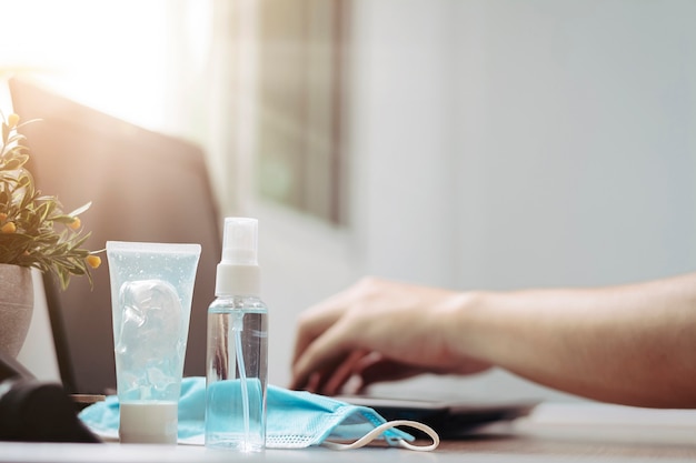 Lavorando sulle loro scrivanie a casa Gel igienizzante per le mani con il concetto di prevenzione delle maschere chirurgiche mediche