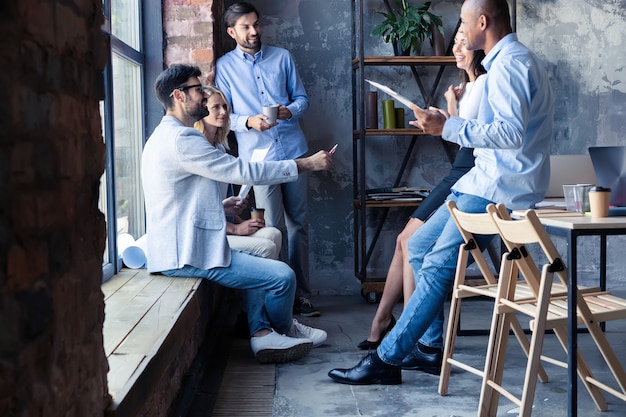 Lavorare come una squadra. Tutta la lunghezza dei giovani moderni in abbigliamento casual intelligente che hanno una riunione nell'ufficio creativo