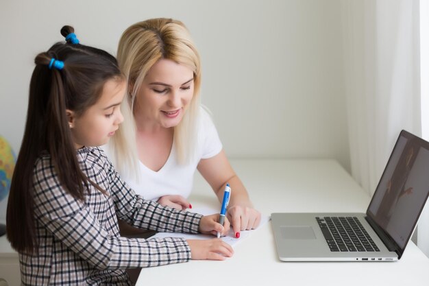 Lavorare da casa con un bambino. Figlia felice che abbraccia la madre. Giovane donna e bambino carino utilizzando laptop. Posto di lavoro libero professionista. Affari femminili, apprendimento a distanza. Momento di stile di vita familiare.