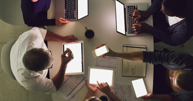 Lavorare fino a tardi spesso porta al successo un'inquadratura dall'alto di un gruppo di uomini d'affari che lavorano insieme