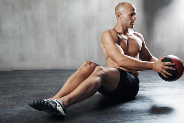 Lavorare i muscoli del core. Inquadratura di un uomo che si allena con una palla medica in palestra.