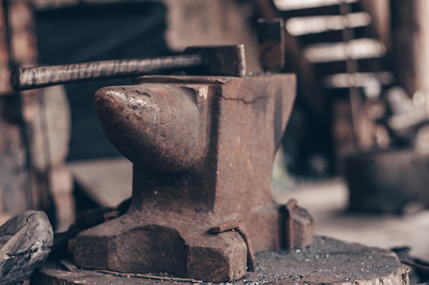 Lavorare il metallo con il martello sull'incudine nella fucina Colpire il ferro all'aperto in officina Lavorazione dei metalli fabbro