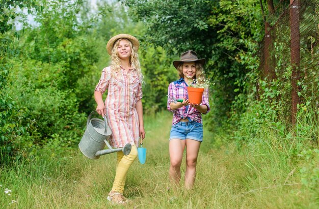 Lavorare in ambiente verde ecologia e protezione dell'ambiente i bambini tengono attrezzi da giardinaggio giornata della terra estate famiglia fattoria agricoltura e agricoltura paese primaverile piccole ragazze contadine nel villaggio