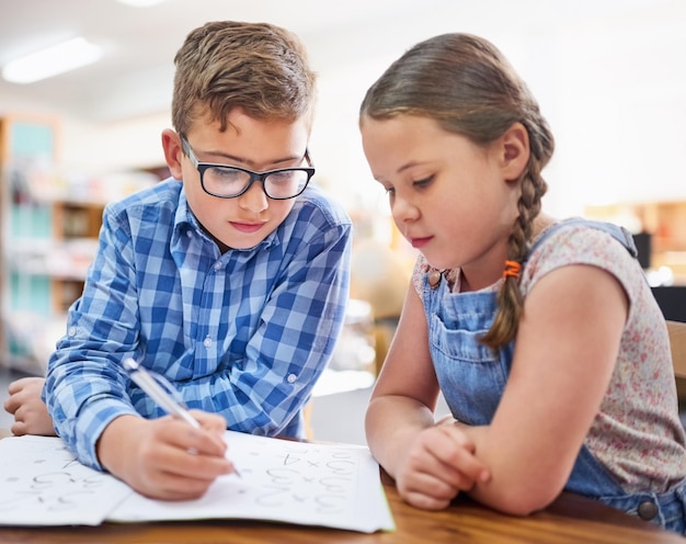 Lavorare sodo per ottenere i voti migliori Inquadratura di due bambini piccoli che lavorano insieme a scuola