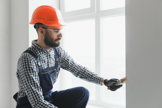 Lavoratore a mano che tiene il pennello dipinto di bianco sul recinto di legno