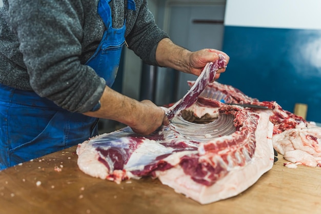 Lavoratore agricolo che taglia carne cruda in una cucina industriale